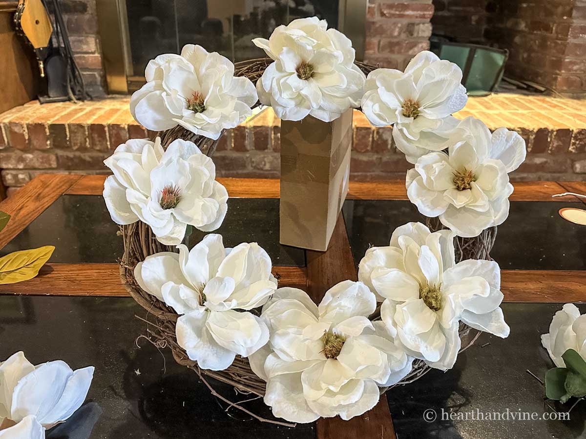 Eight magnolia flowers glued to the face of a grapevine wreath.