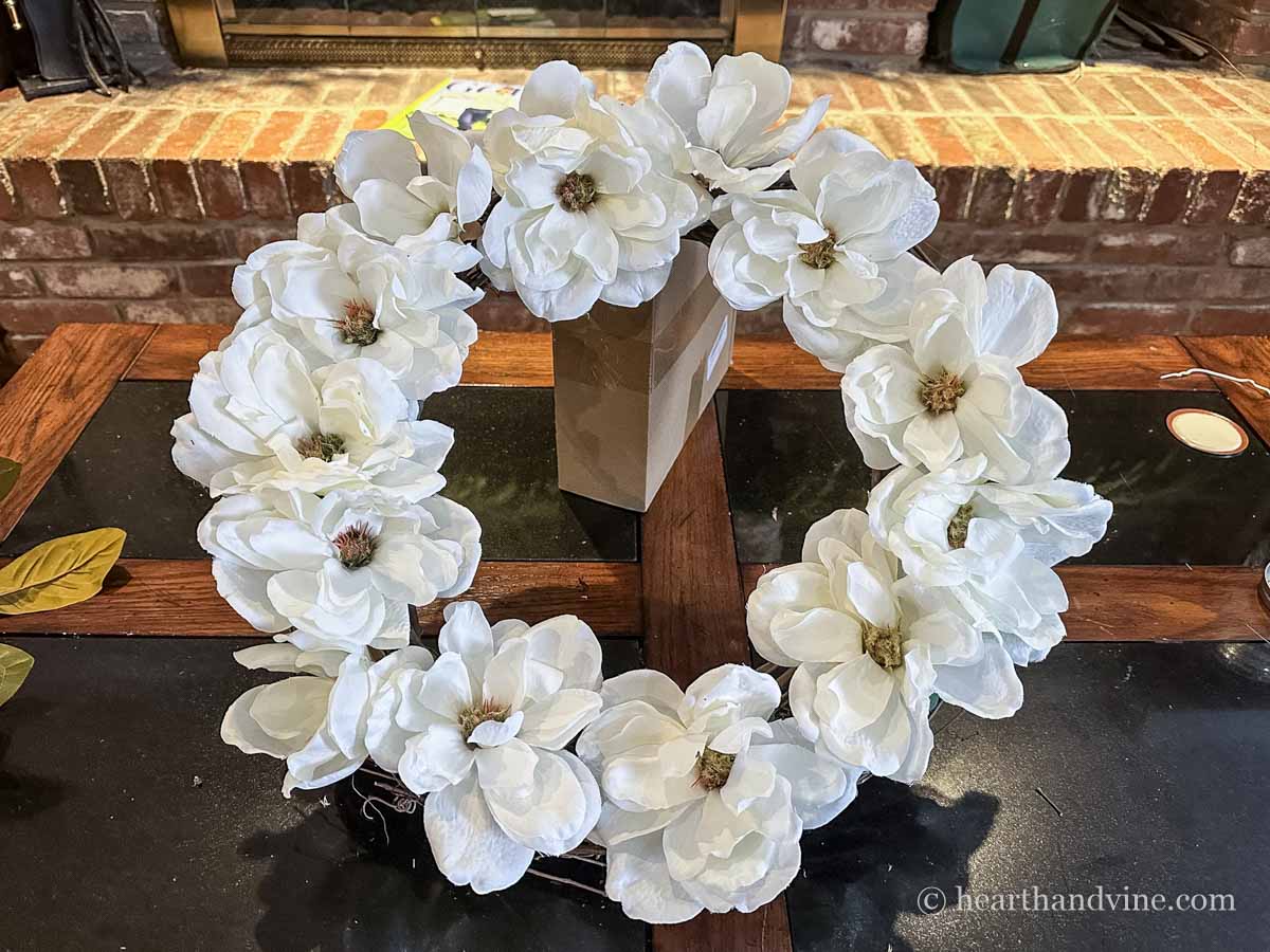 Thirteen white magnolia flowers glued to the face of a grapevine wreath form.