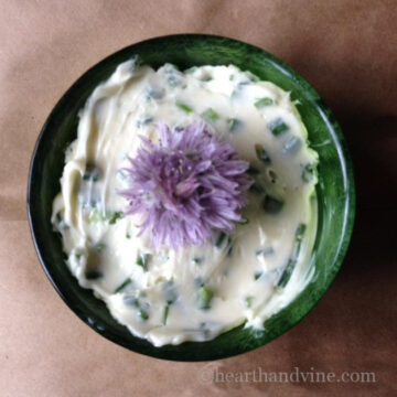 Chive butter in a small bowl with a chive blossom on top.