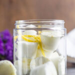 An open jar of lemon scented shower steamers and a few sprigs of lemon peel.