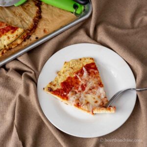 A slice of chicken parm pizza on a plate with a fork.