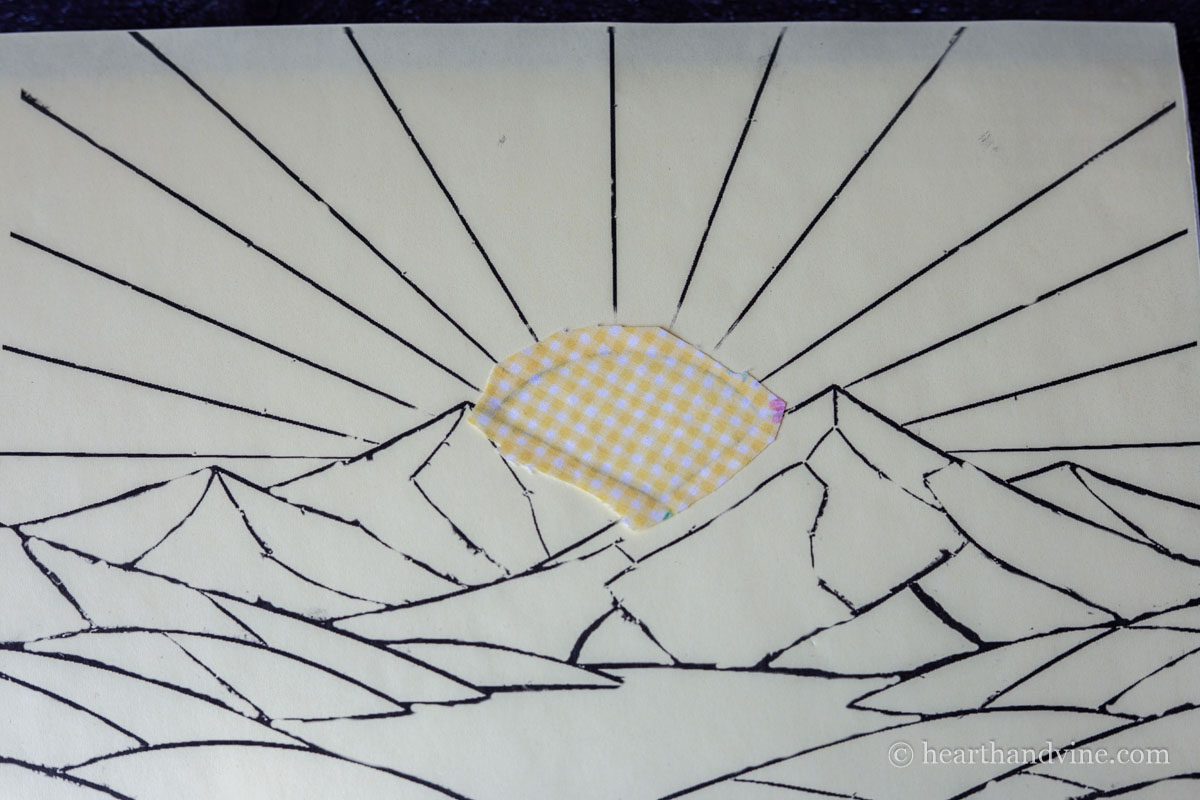 The cut out fabric placed onto the adhesive on the foam board.