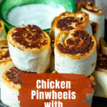 Stacked chicken pinwheels with ranch sauce on the side.