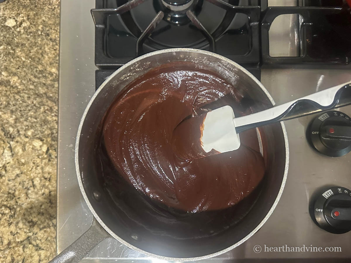 Chocolate ganache in a saucepan on the stove.