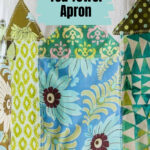 View of the bottom of a tea towel apron with houses applique.