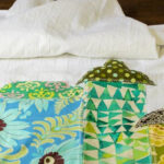 A white apron with colorful fabric houses appliqued at the bottom.