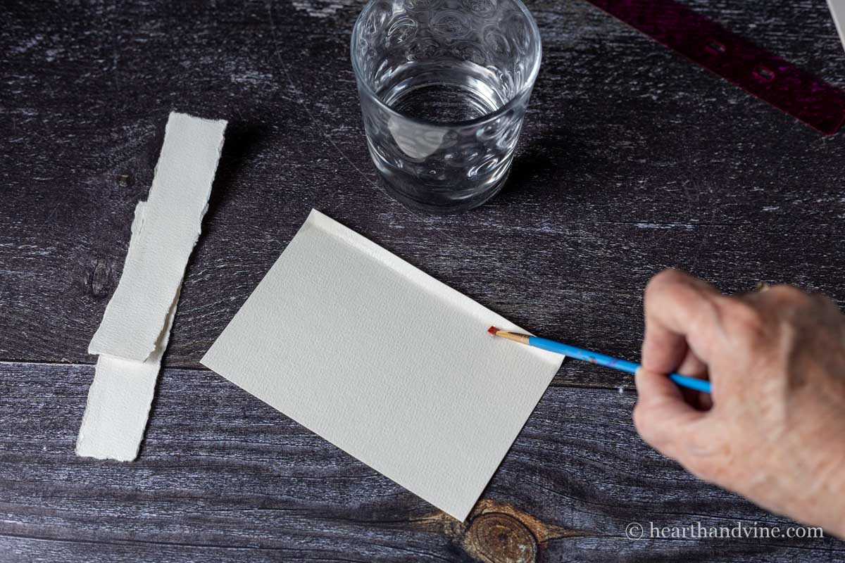 Folded heavy white paper with a paintbrush painting water in the crease.
