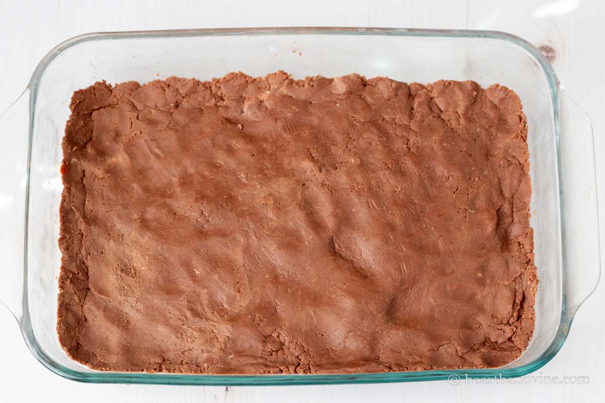Chocolate shortbread dough pressed into a glass baking pan.