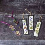 Five pressed flower bookmarks. Three on paper and two with plastic lamination sheeting.