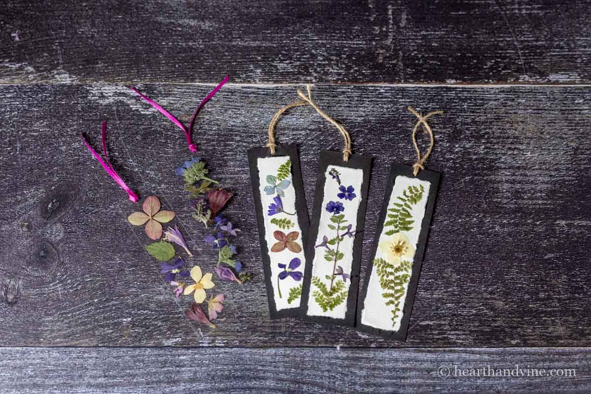Five pressed flower bookmarks. Three on paper and two with plastic laminating sheets.