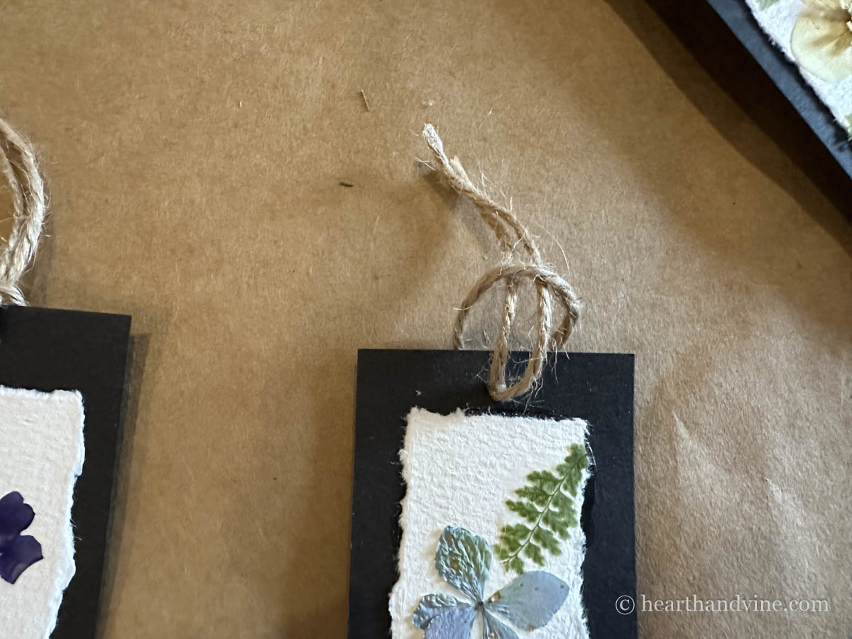 Pulling the twine through the loop to attach it to the bookmark punched hole.