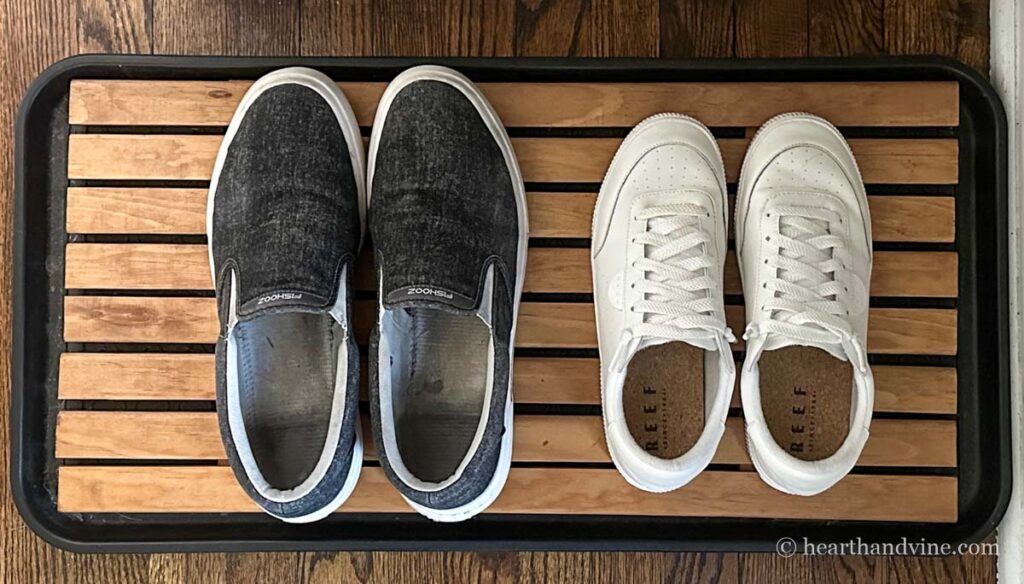 Wooden boot tray with two pairs of shoes on it.