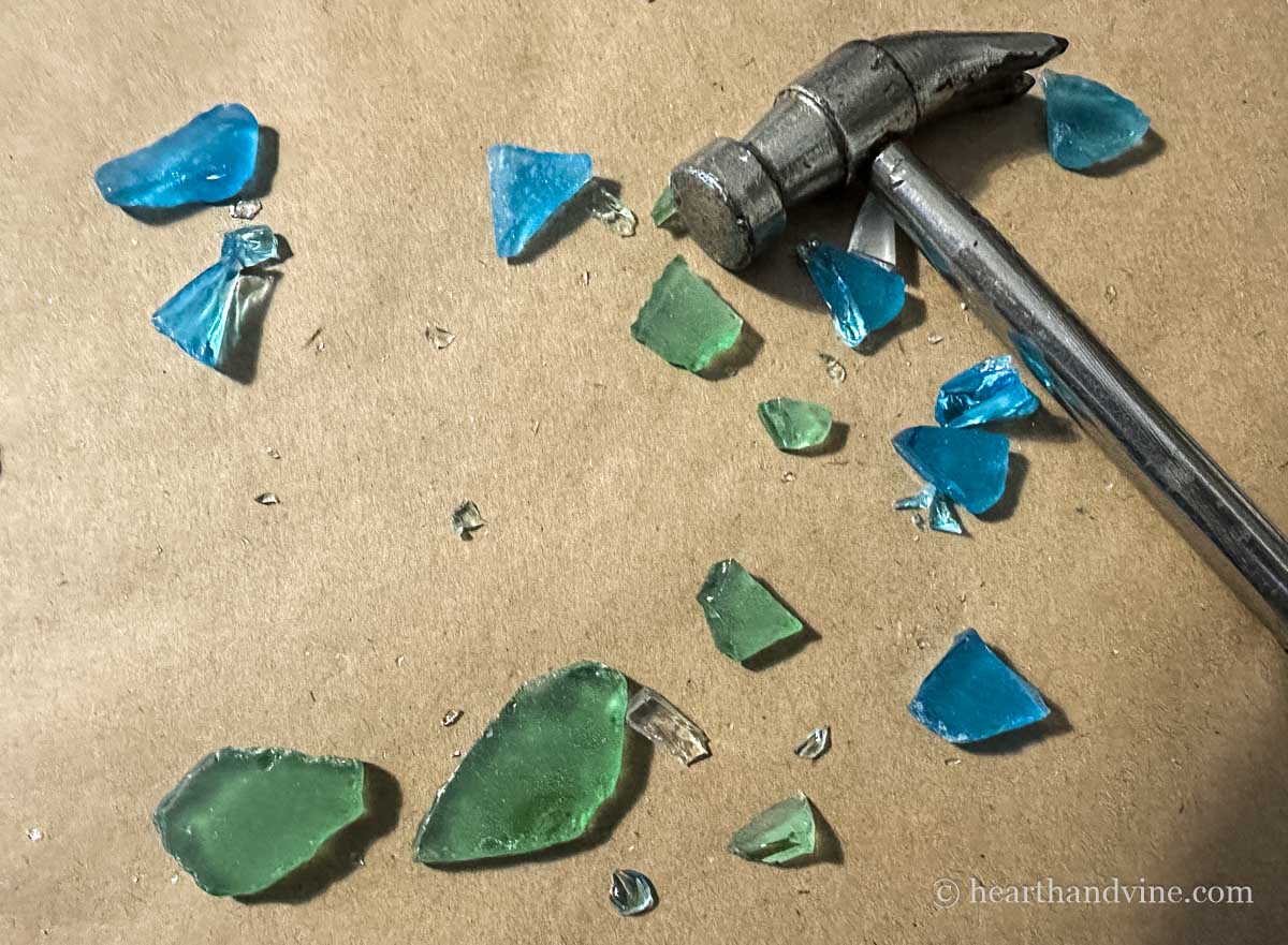 A small hammer in the midst of broken pieces of sea glass.