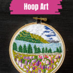 Mini embroidery hoop with a landscape of flowers, water and mountains.