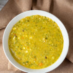 An aerial view of a bowl of zucchini corn chowder in a white bowl.