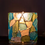 Glowing sea glass candle holder lit in the dark.