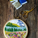 Mini embroidery hoop art next to embroidery floss cards.