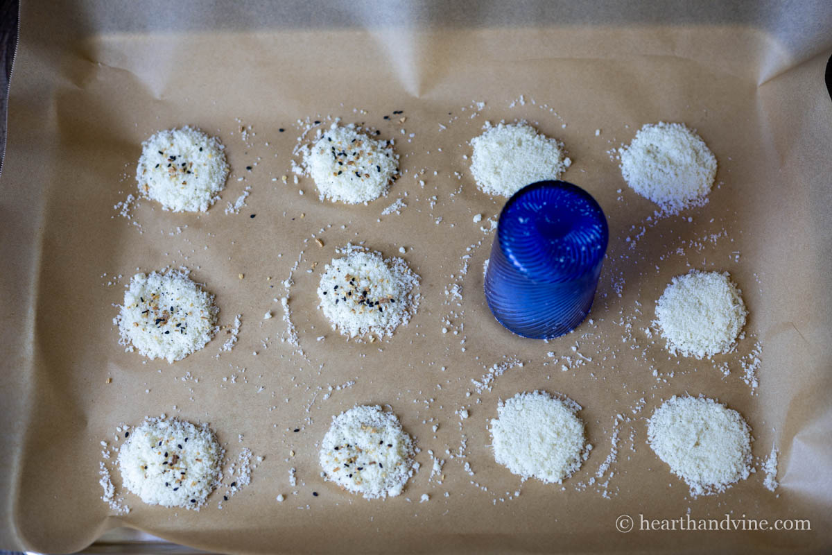 A small blue cup set upside down on a mound of parmesan cheese to mold it into a circle.