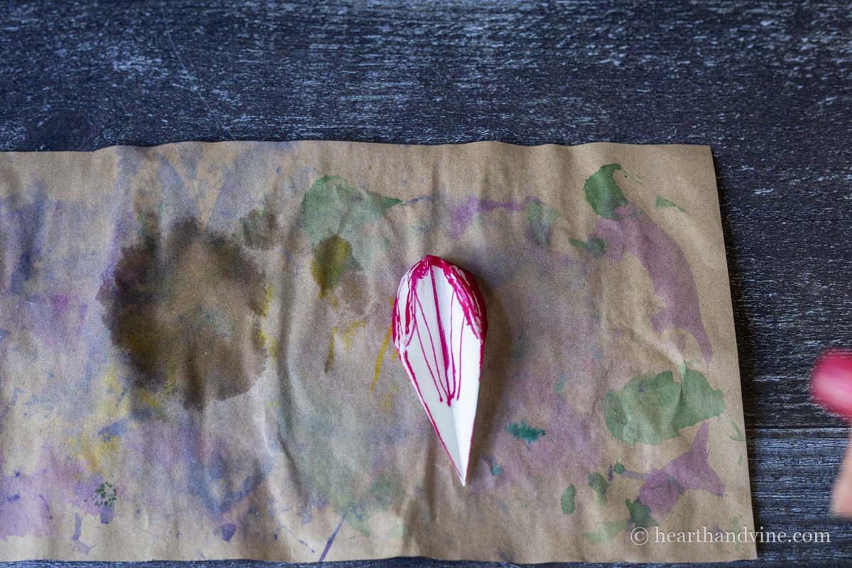 Folded coffee filter colored edges with pink marker.