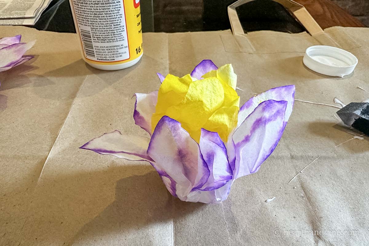 Purple edged coffee filter flower glue onto ball with yellow center.
