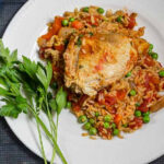 An aerial view of a plated portion of arroz con pollo with parsley garnish.
