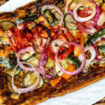 Partial view of a whole veggie tart on a platter.