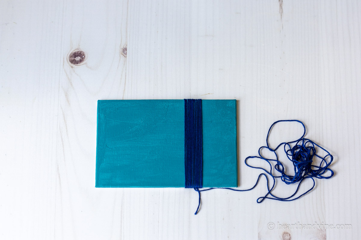 Blue thread wrapped around a canvas board.