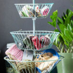 A 3 tiered basket stand with tapes and rolls of twine/string.
