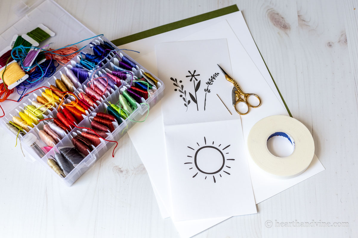 The supplies for card embroidery including tape, scissors, embroidery thread, and paper.