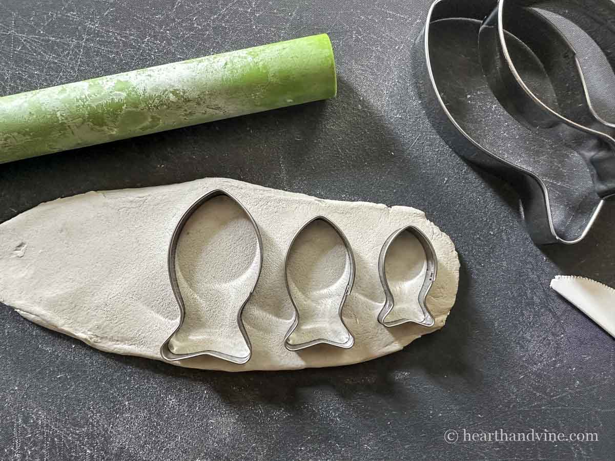 Fish cookie cutters in three sizes pressed into rolled out air dry clay.