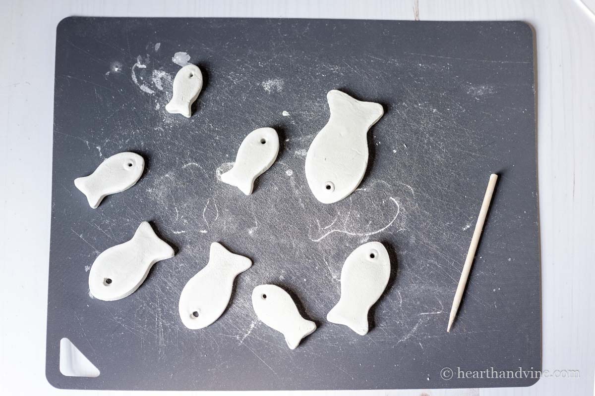 Dried cut out fish with a eye hole next to a wooden skewer on a plastic mat.