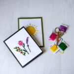Two embroidered cards with embroidery threads on the side.