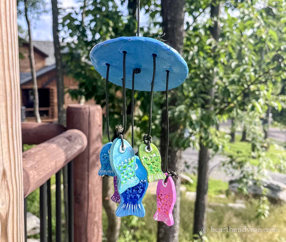 A clay fish wind chime hanging on a porch.