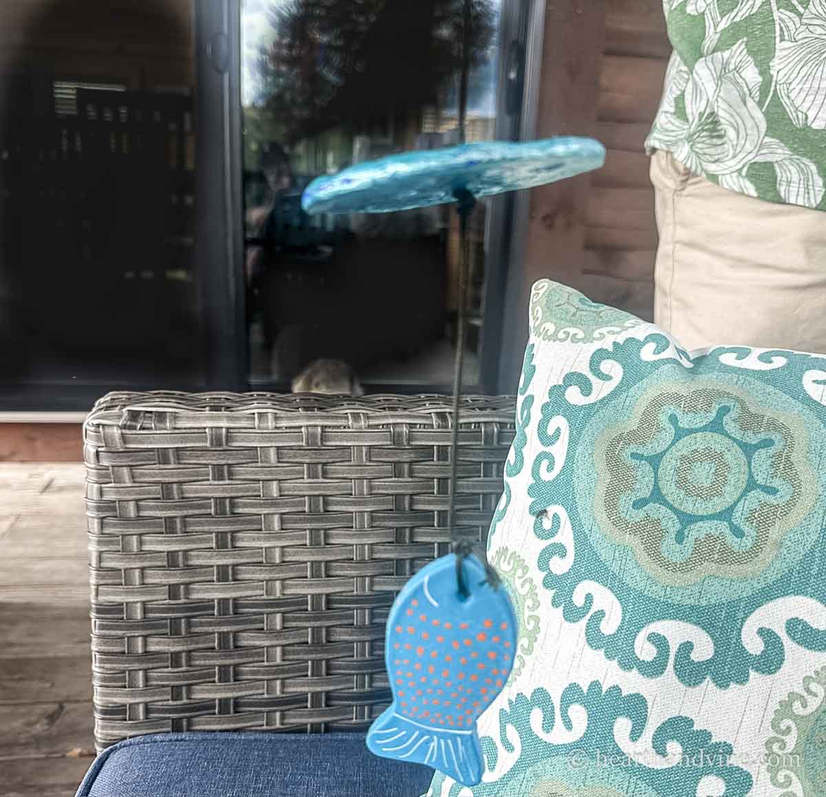A large painted clay fish hanging through the center of a clay disc with a D-ring on the other end.