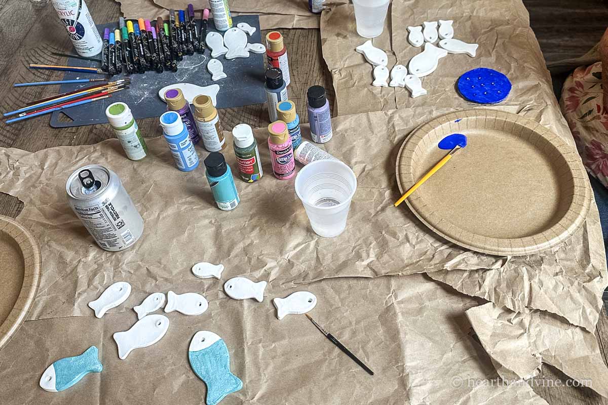 A table cover with paints and air dry clay fish in the process of being painted.