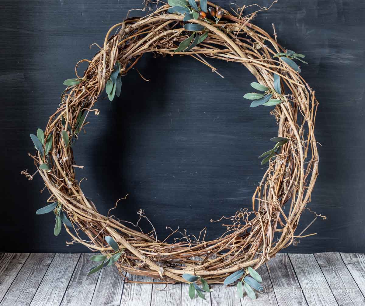 An old grapevine wreath with a few pieces of green leaves tucked in.