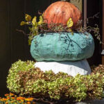 Three heirloom stacked paper mache pumpkins with dried hydrangeas at the base.