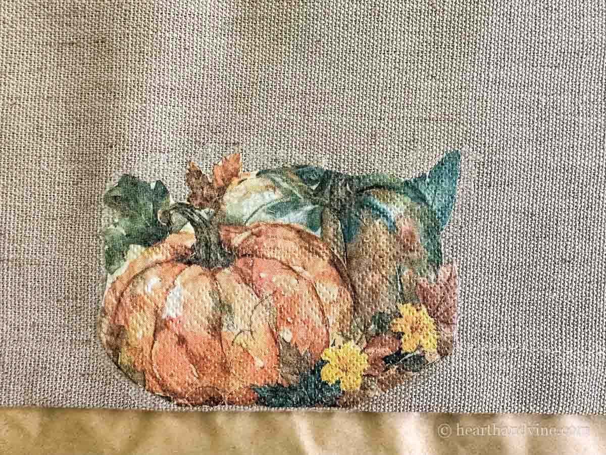 Pumpkin napkin glued to tan fabric table runner.