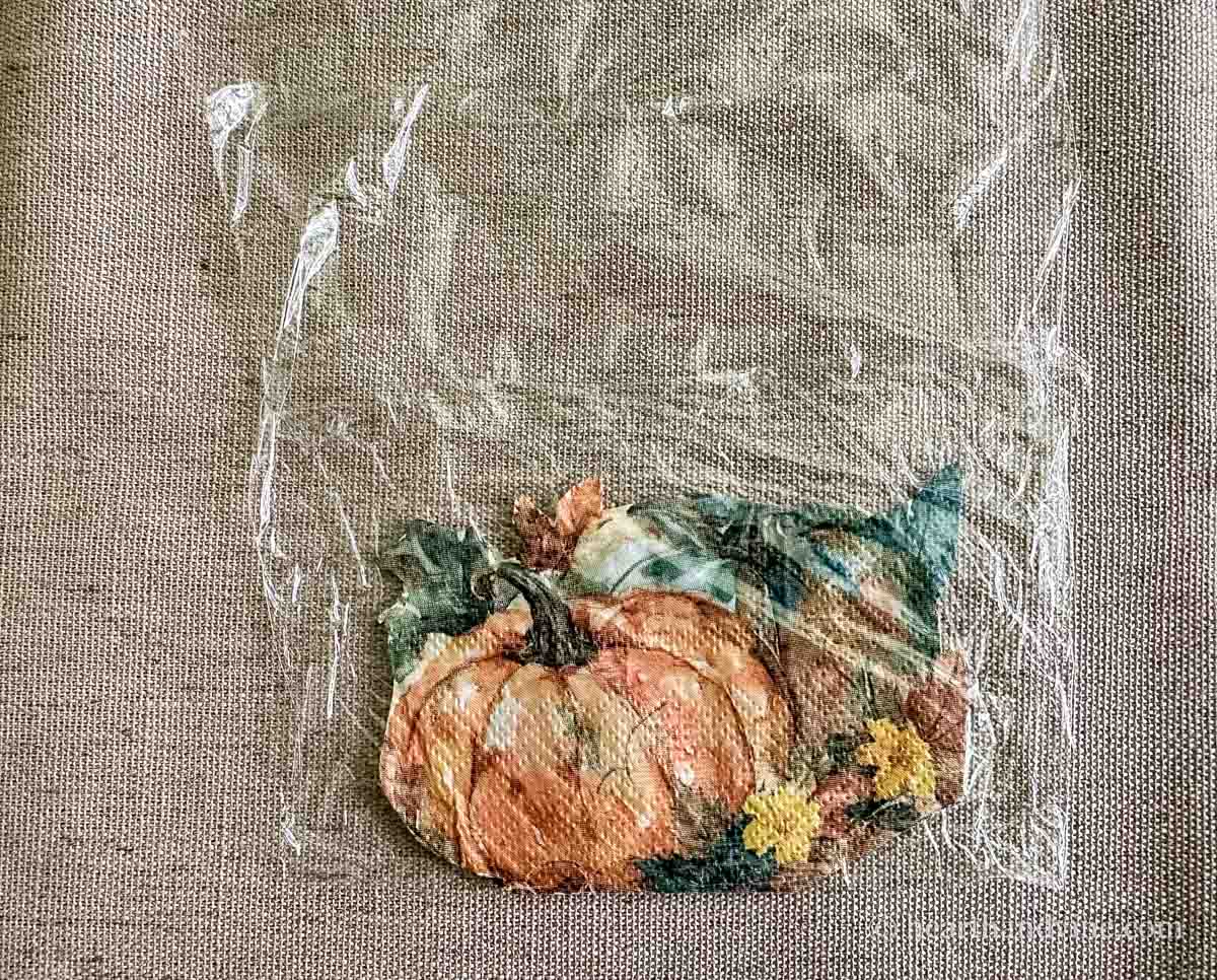 Pumpkin napkin sandwiched in plastic wrap.