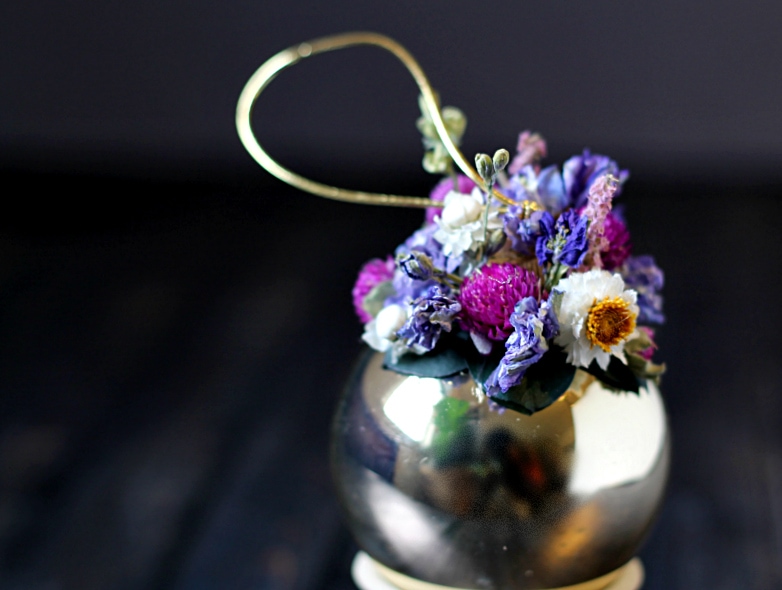 Close up of the dried flowers on top of a gold Christmas ball.