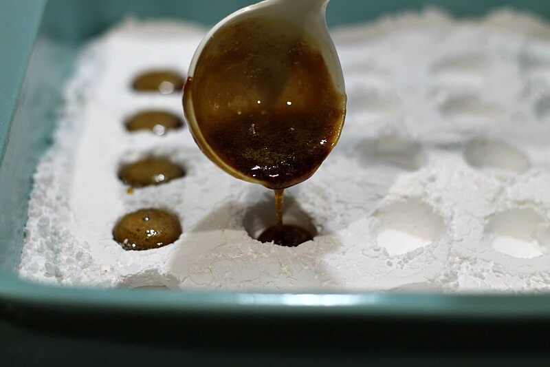 Dropping cough drop mixture into powdered sugar