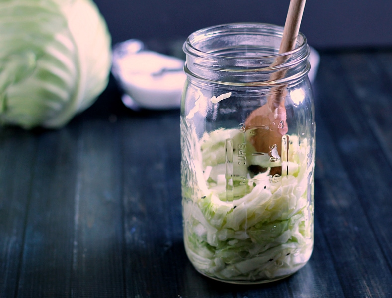 Mashing shredded cabbage in mason jar