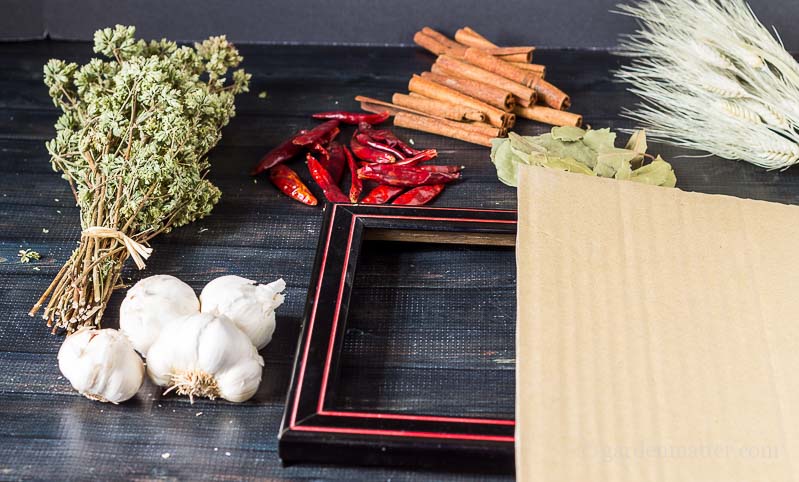 Materials including cinnamon sticks, dried oregano flowers, bay leaves, red peppers and a black picture frame.
