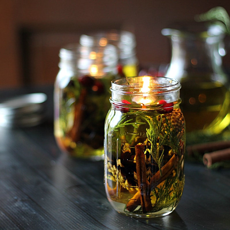 Mason jar oil candles with natural materials like cinnamon sticks and a floating wick.