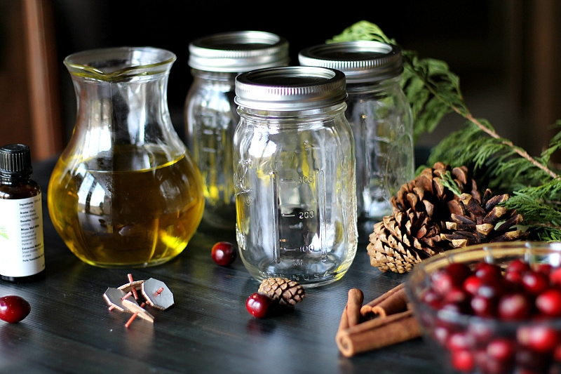 Mason Jar Oil Candle Lamp materials of fresh cranberries, cinnamon stickes, pine cones and floating wicks.